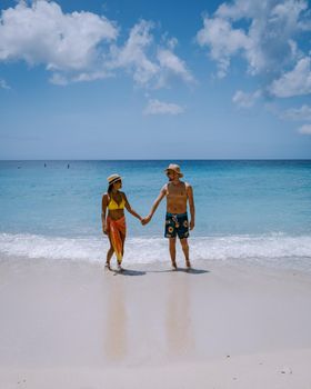 View of the white beach Grote Knip, Curacao, Netherlands with a blue ocean Curacao Caribbean Island tropical beach with palm trees, couple men and woman visiting Curacao on vacation at the beach