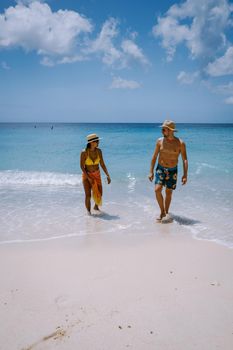 View of the white beach Grote Knip, Curacao, Netherlands with a blue ocean Curacao Caribbean Island tropical beach with palm trees, couple men and woman visiting Curacao on vacation at the beach