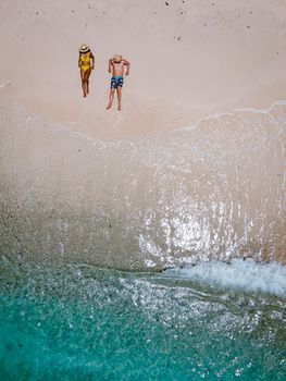 Playa Kalki Curacao tropical Island in the Caribbean sea, Playa Kalki western side of Curacao Caribbean Dutch Antilles azure ocean, drone aerial view of couple men and woman on the beach from above