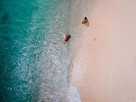 Playa Kalki Curacao tropical Island in the Caribbean sea, Playa Kalki western side of Curacao Caribbean Dutch Antilles azure ocean, drone aerial view of couple men and woman on the beach from above