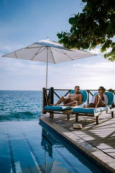 Relaxing summer beach , Sunbathing deck and private swimming pool with Palm trees near beach and panoramic sea view at luxury house Curacao, men and woman by swim pool infinity pool