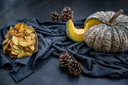 Flat Lay composition with delicious of Homemade crispy pumpkin chips on Black stone texture. Oblique view from the top.