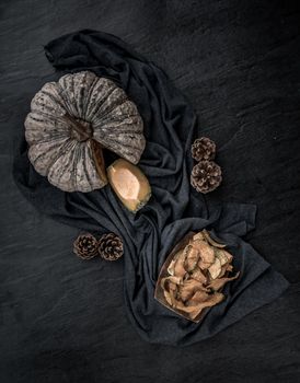 Flat Lay composition with delicious of Homemade crispy pumpkin chips on Black stone texture. Top view.