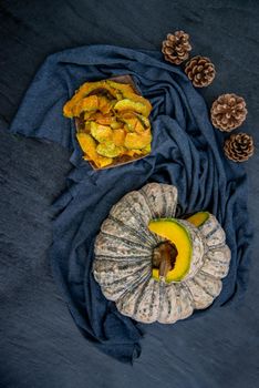 Flat Lay composition with delicious of Homemade crispy pumpkin chips on Black stone texture. Top view.