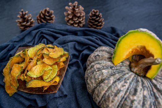 Flat Lay composition with delicious of Homemade crispy pumpkin chips on Black stone texture. Oblique view from the top.
