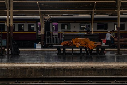 Bangkok, thailand - Jul 7, 2019 : A monk is sleep on wooden chairs are waiting for trains in the area provided at Main railway station of Hua Lamphong, Selective focus.