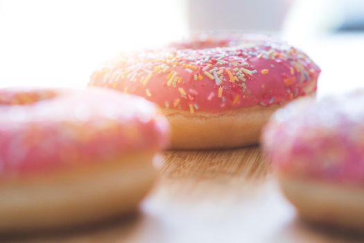 Sugar sprinkled pink donut on wooden plate