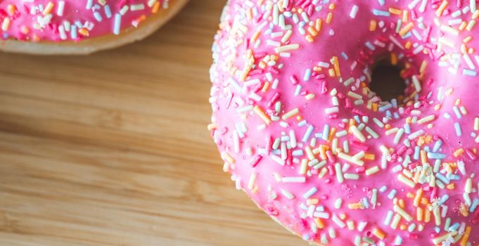Sugar sprinkled pink donut on wooden plate