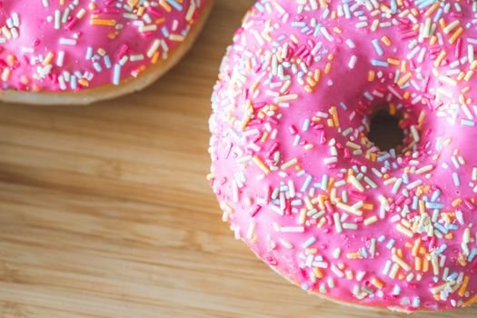 Sugar sprinkled pink donut on wooden plate
