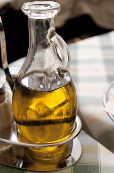 Detail of a glass jug with olive oil at a table