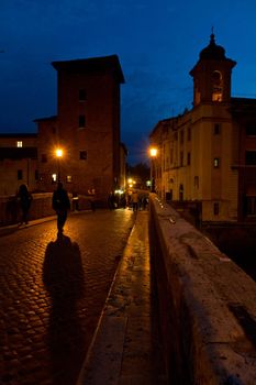 A wide shot of the houses and churches at Tiberine Island at Rome at sunset against a dark blue sky