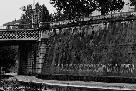 Detail of a graffiti wrote in white paint in a wall by the Tiber river in Rome