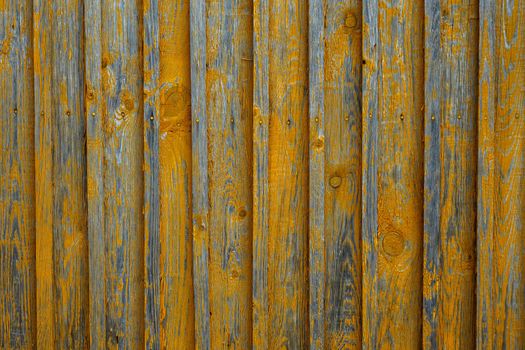Wall of wooden boards is painted with yellow paint.