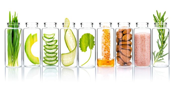 Homemade skin care and body scrubs with natural ingredients wheat grass ,avocado ,aloe vera ,cucumber ,himalayan salt  ,honeycomb ,almonds, centella asiatica and rosemary  in glass bottles isolate on white background.