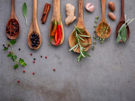 Various of spices and herbs in wooden spoons. Flat lay spices ingredients chili ,peppercorn, rosemarry, thyme,star anise ,sage leaves and sweet basil on concrete background.