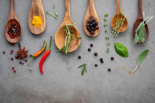 Various of spices and herbs in wooden spoons. Flat lay spices ingredients chili ,peppercorn, rosemarry, thyme,star anise ,sage leaves and sweet basil on concrete background.