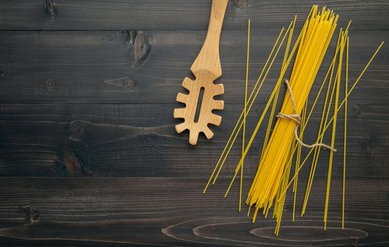 The thin spaghetti on black wooden background. Yellow italian pasta with copy space . Italian food and menu concept.