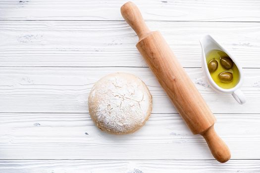 Raw pizza dough and rolling pin on wooden background