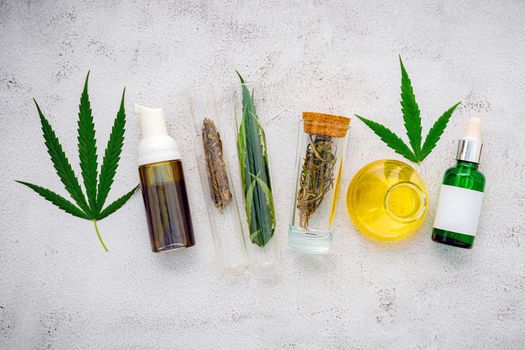 Glass bottle of cannabis oil and hemp leaves set up  on concrete background.