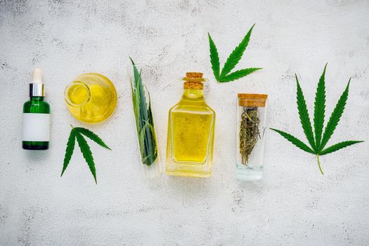 Glass bottle of cannabis oil and hemp leaves set up  on concrete background.