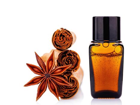 Cinnamon essential oil bottle with Ceylon cinnamon sticks and anise star isolated on white background .