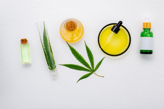 Glass bottle of cannabis oil and hemp leaves set up  on white background.