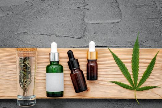 Glass bottle of cannabis oil and hemp leaves set up  on concrete background.