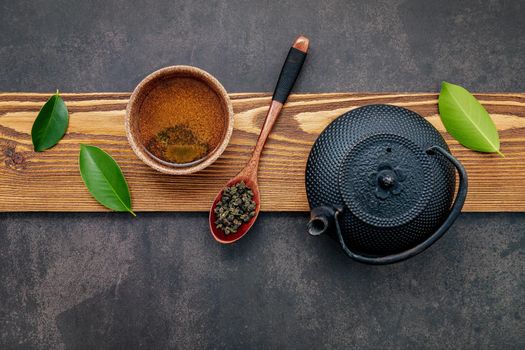 Black cast iron tea pot with herbal tea set up on dark stone background.