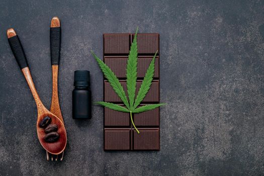 Food conceptual image of  cannabis leaf  with dark chocolate and fork on dark concrete background.