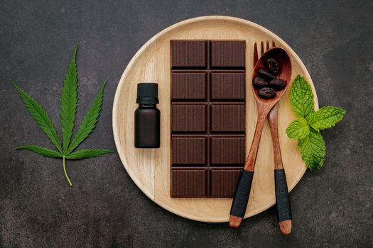 Food conceptual image of  cannabis leaf  with dark chocolate and fork on dark concrete background.