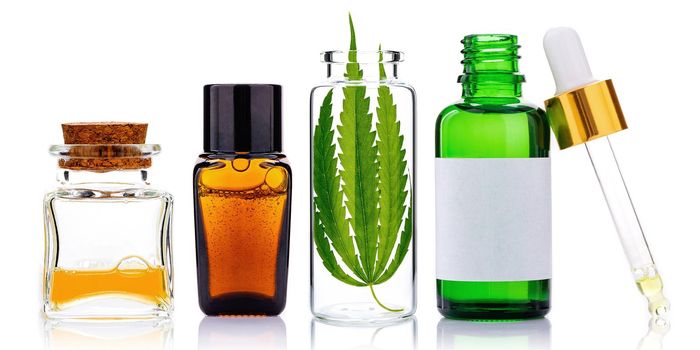 Glass bottles of cannabis oil and hemp leaves isolated on white background. Concept of using hemp in medicine.

