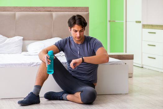 Young handsome man doing morning exercises in the hotel room