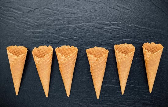 Flat lay ice cream cones collection on dark stone background . Blank crispy ice cream cone with copy space for sweets menu design.