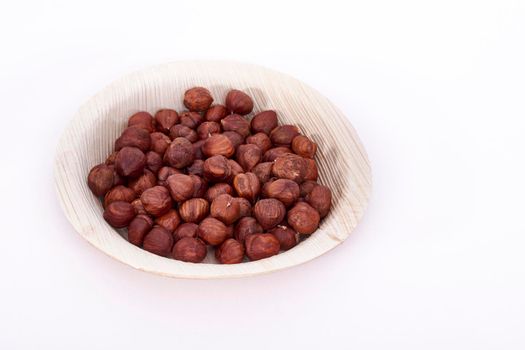Areca leaf bowl of Hazel nuts on a white background