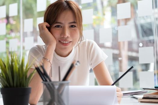 Photo of beautiful happy woman looking at camera while sitting on workplace at home office.