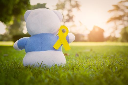 Bear on park,Yellow ribbon symbolic color for Sarcoma Bone cancer awareness and suicide prevention with toy bear. The cancer, health, help, care, support, hope, illness, healthcare concept