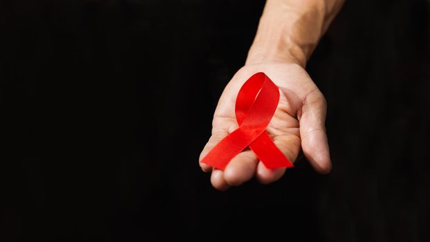World AIDS day awareness ribbon,Female hands holding red ribbon HIV,Healthcare and medicine concept.