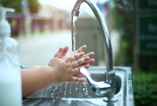 Child washing his hands with soap on outdoor, hygiene and cleaning concept