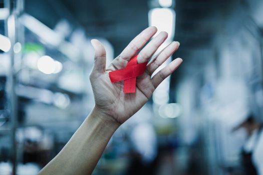 World AIDS day awareness ribbon,Female hands holding red ribbon HIV,Healthcare and medicine concept.