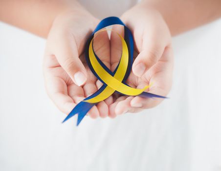 Close-up view of  Child holding Down Syndrome Day ribbon