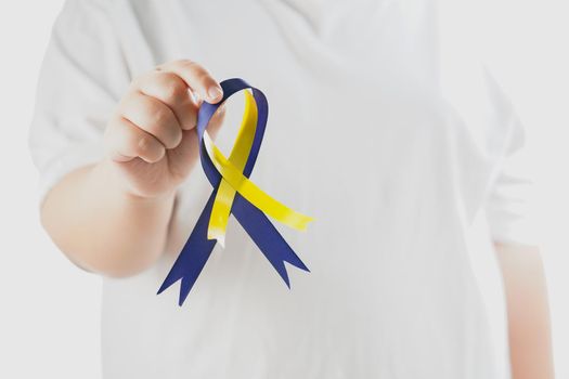 Close-up view of  Child holding Down Syndrome Day ribbon