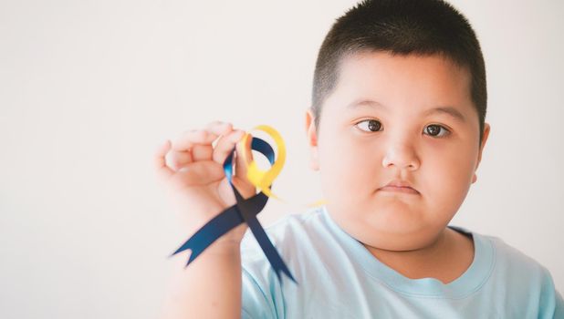 Cute kid with down's syndrome holding ribbon