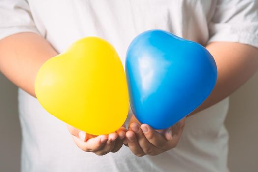 Heart-shaped balloons represent the sign of Down syndrome children. Balloons on hand