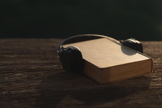 Audio book concept. Headphones and old book on wood