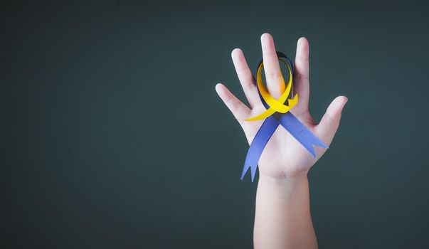 World down syndrome day with blue yellow ribbon bow color on hand