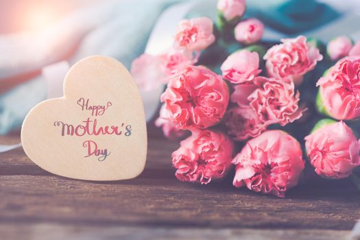 Still life with sweet carnation flowers on wooden table, Mothers day concept With a message for Happy Mother's Day on a wooden heart