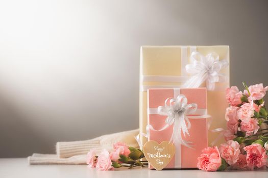 Still life with sweet carnation flowers and gift on table, Mothers day concept