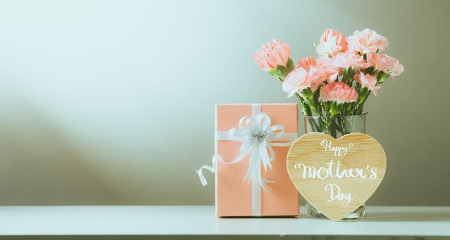 Still life with sweet carnation flowers and gift on table, Mothers day concept, Vintage filter color