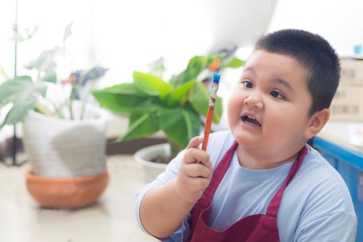 Boy holding a paintbrush in the house is a new era of learning and detention.