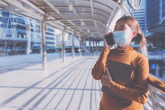 Woman wearing a mask. Doing business by talking on the phone on the city hallway.